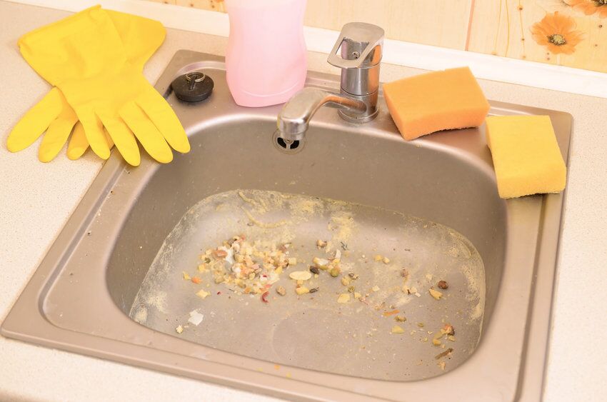 Close up on dirty clogging kitchen sink drain with food particles Close up on dirty clogging kitchen sink drain. Blur and selective focus of sink hole clogging up with food particles