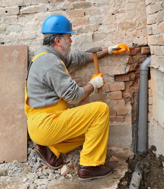 Plumber at construction site installing sewerage tube Home renovation, plumber install sewerage pipe at construction site using hammer and chisel