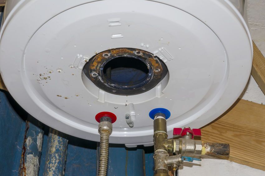 The repair process of the leaked boiler. The repair process of the leaked boiler. Inside of the broken water heater or boiler with electric wires and pipes for installation of the hoses with rust and burn. Selective focus