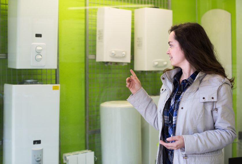 Woman choosing heating water converter Young longhaired woman choosing heating water converter in hypermarket