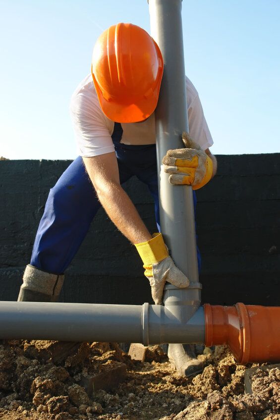 Plumber assembling pvc sewage pipes in house foundation Plumber assembling pvc sewage pipes in house foundation